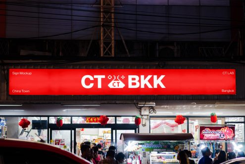 Red illuminated sign mockup with editable text reading CT BKK over a busy street, ideal for designers creating urban signage graphics.